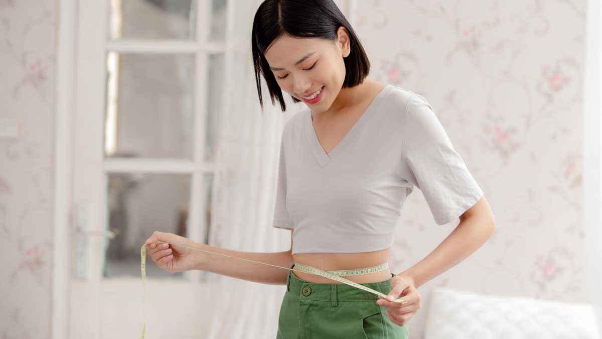 メジャーでウエストを測定する女性